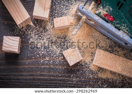 Electric jigsaw sawdust and wooden planks on vintage wood board top view image construction concept.