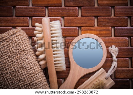 Wood massager looking-glass body scrubber and peeling brush on textured wooden mat sauna concept.