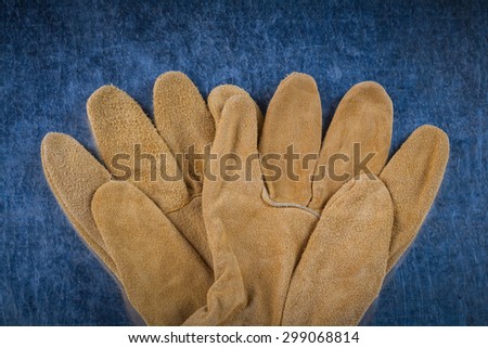 Leather brown construction gloves on scratched metallic surface close up version building concept.