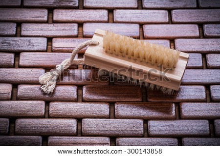 Wood scrubbing brush on textured table wooden mat top view healthcare concept.