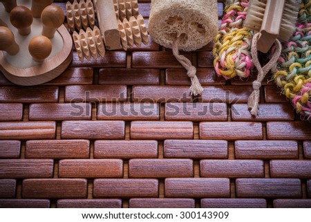 Fluffy body scrubber wood peeling brush massagers and loofah on checked wooden place mat sauna concept.
