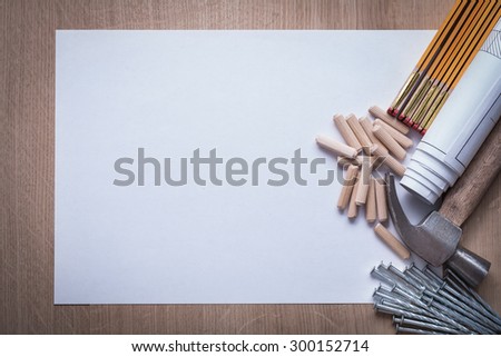 Wooden meter rolled blueprints blank paper nails claw hammer woodworking dowels on wood board copy space construction concept.