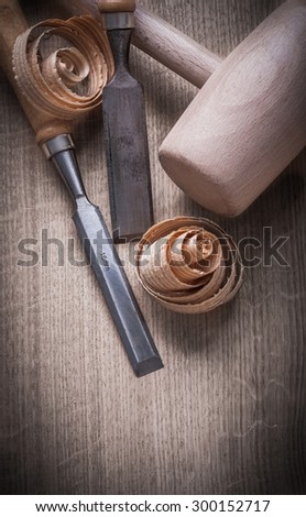 Wooden mallet curled up shavings flat chisels on wood board construction concept.
