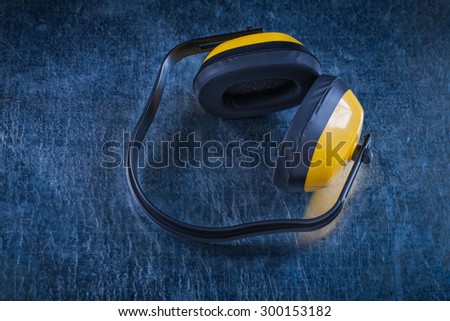 Noise reduction ear protectors on scratched metallic surface construction concept.