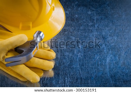 Leather working gloves hard hat and claw hammer on scratched metallic surface construction concept.