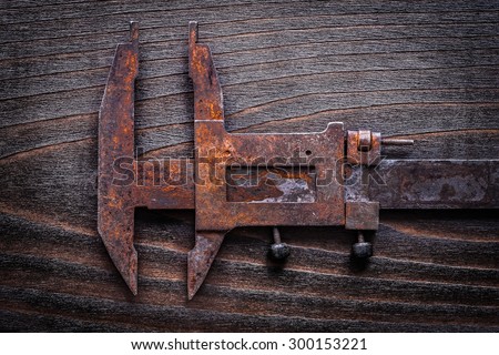 Rusted old-fashioned measuring slide caliper on vintage wooden board construction concept.