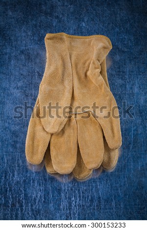 Pair of leather brown protective gloves on scratched metallic surface building concept.