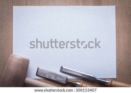 Flat chisels wooden mallet and clean sheet of paper on wood board copyspace construction concept.