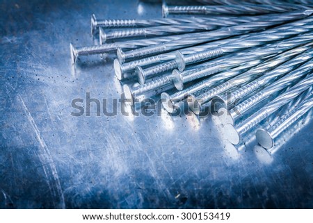 Heap of stainless construction nails on scratched metallic surface building concept.