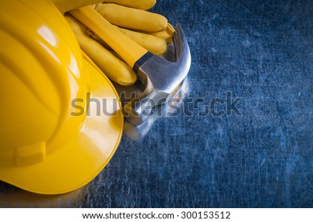 Leather protective gloves building helmet and claw hammer on metallic surface copy space image construction concept.