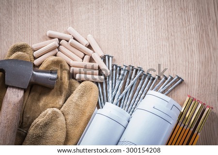 Collection of wooden meter dowels construction drawings claw hammer leather safety gloves and steel nails on wood board maintenance concept.