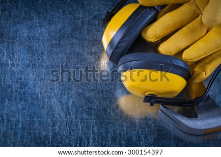 Noise insulation headphones claw hammer and protective gloves on metallic background copy space image construction concept.