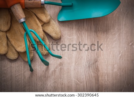 Leather working gloves gardening trowel and rake on wood board horizontal view agriculture concept.