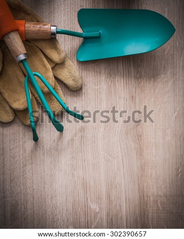 Set of leather working gloves gardening trowel and rake on wood board agriculture concept.