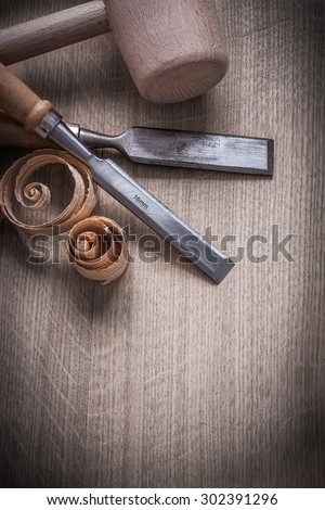 Wooden hammer curled up planning chips flat chisels on wood board construction concept.