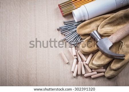 Wooden meter dowels construction drawings claw hammer pair of safety gloves and nails on wood board maintenance concept.