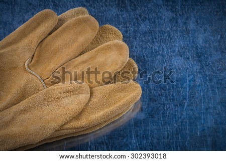 Pair of leather brown protective gloves on scratched metallic surface copy space image building concept.