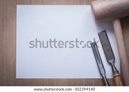 Firmer chisels lump hammer and clean sheet of paper on wooden board copy space construction concept.