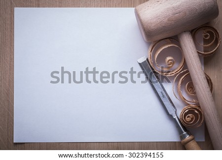 Curled shavings firmer chisels wooden mallet and blank sheet of paper on wood board copy space image construction concept.