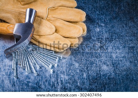 Leather protective working gloves construction nails and claw hammer on scratched metallic surface top view building concept.