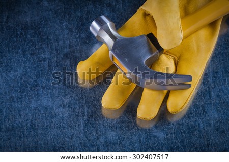 Leather protective glove with claw hammer on scratched metallic background construction concept.
