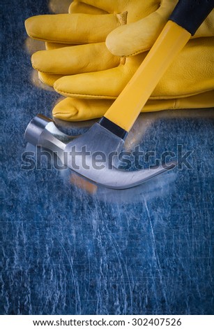 Leather protective gloves with metal claw hammer on scratched metallic background construction concept.