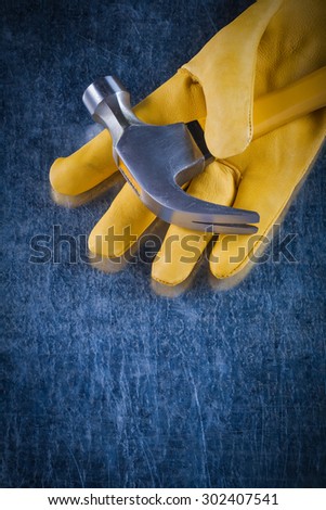 Leather yellow safety glove with claw hammer on scratched metallic background construction concept.