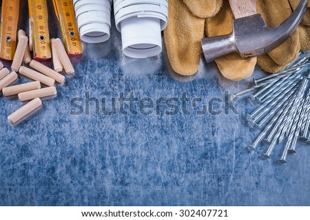 Blueprints claw hammer leather protective gloves wooden meter steel nails and dowels on scratched metallic background construction concept.