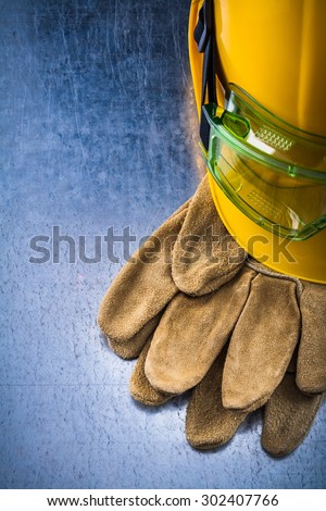 Construction leather gloves building helmet and plastic protective eyewear on scratched metallic background maintenance concept.