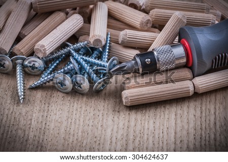 Woodworking dowels metal construction nails insulated screwdriver on wood board.