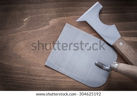 Putty knife bricklaying trowel on wooden surface top view image.