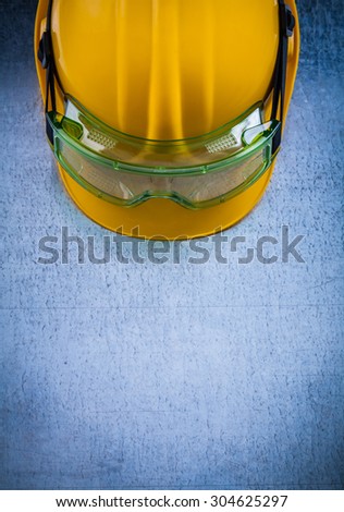 Safety building helmet and plastic glasses on metallic background construction concept.