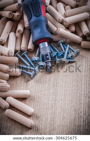 Heap of wooden dowels stainless construction nails and insulated screwdriver.