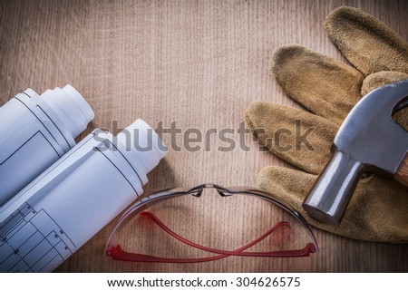 Construction plans goggles claw hammer brown leather protective gloves.