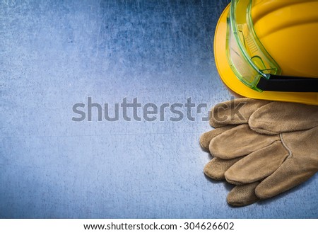 Construction leather gloves hard hat and plastic protective glasses on scratched metallic background copy space image maintenance concept.