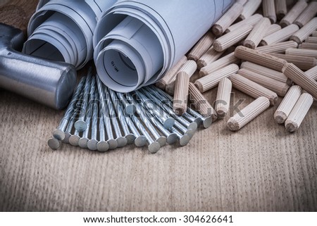 Construction drawings claw hammer pile of woodworking dowels and nails.