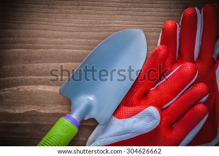 Gardening working gloves and hand spade on wooden background.