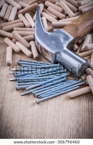 Wooden dowels steel nails and claw hammer construction concept.
