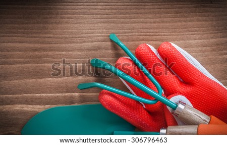 Working gloves hand spade and rake on wooden surface.