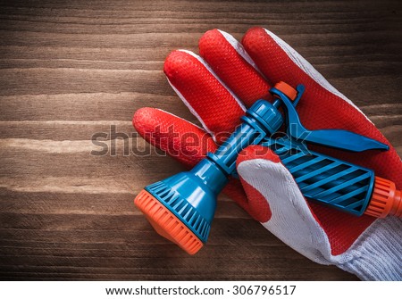 Working glove and water hose nozzle on wooden surface.