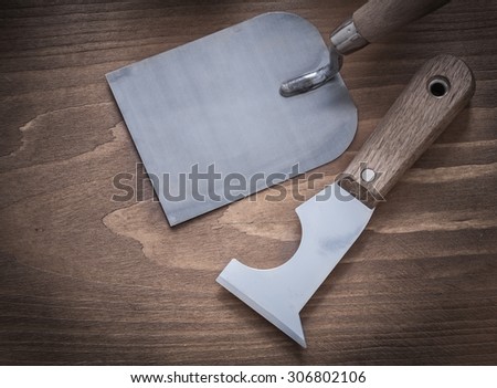 Metal putty knife bricklaying trowel on wooden surface construction concept.