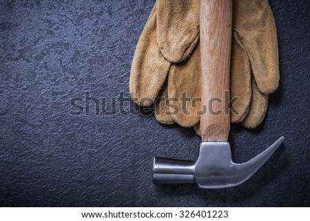 Leather safety gloves claw hammer on black background construction concept.