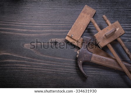 Age-old claw hammer square ruler carpenter gauge on wood board.