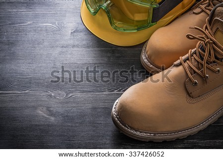 Protective spectacles building helmet safety boots on wooden board.