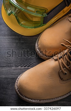 Protective spectacles hard hat safety boots on wooden board.