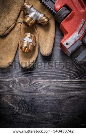Adjustable wrench connector fittings safety gloves on wooden board.