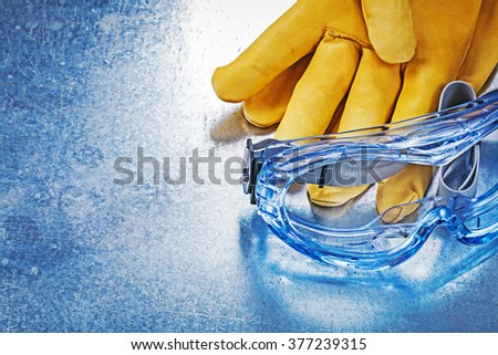 Horizontal version of safety glasses gloves on metallic background.
