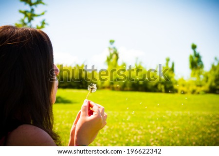 Blowing a Dandelion - Young women blowing a dandelion