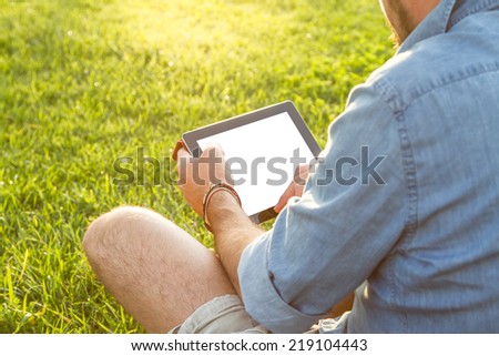 Adult man enjoys his digital tablet outdoor at sunset - Clipping Path of the screen included