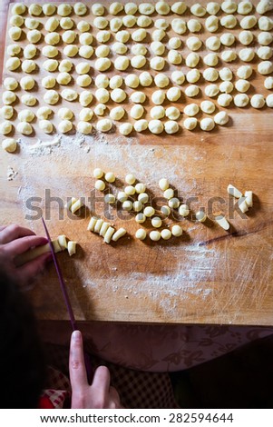 Orecchiette. Cooking of Italian handmade pasta, typical of the Puglia region in southern Italy. Young adult girl is cutting the dough